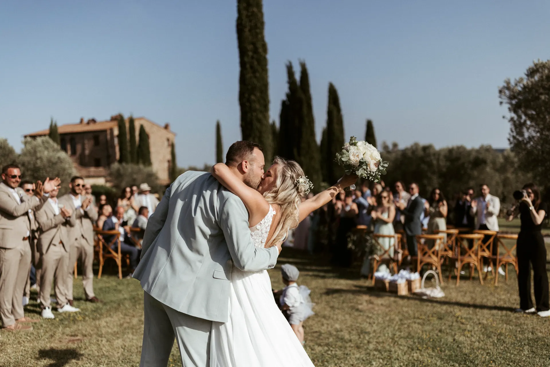 Il bacio degli sposi davanti agli invitati che applaudono, con il Convento di Montepozzali alle spalle